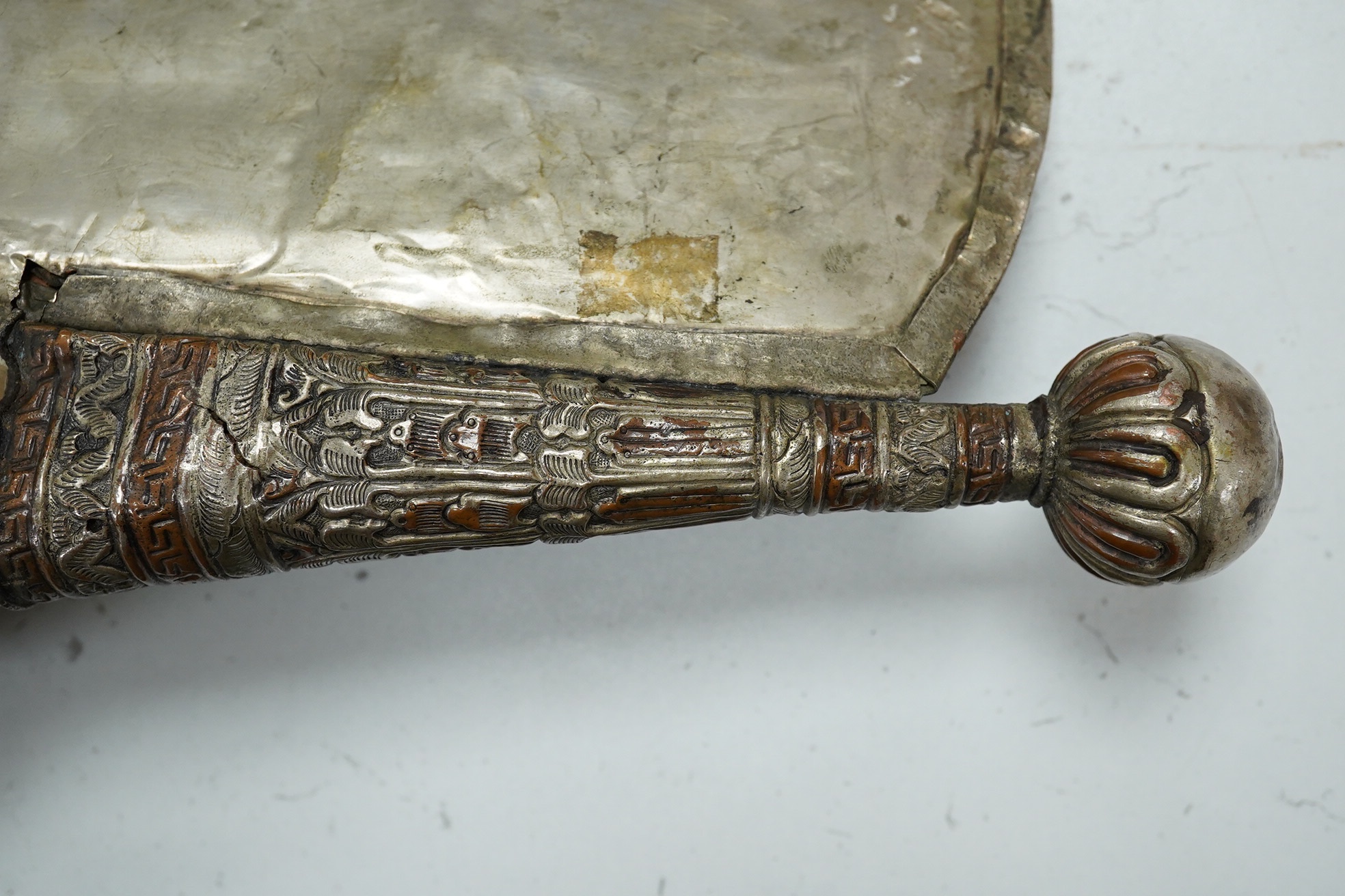 A Tibetan repoussé work cowrie shell trumpet, early 20th century, set with a cabochon, 37cm high. Condition - fair to good